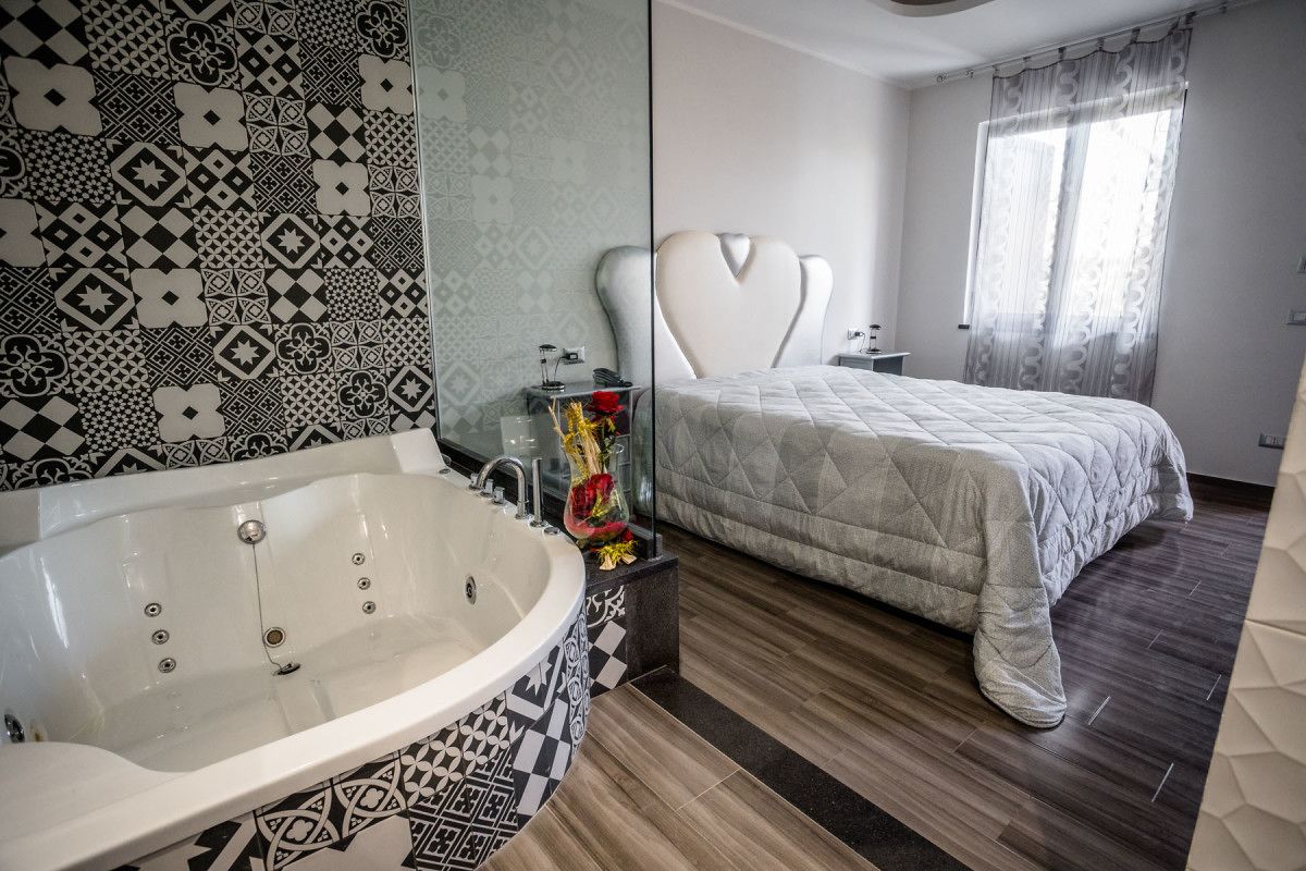 A modern bathroom with a freestanding bathtub, a large mirror, and a patterned wall.