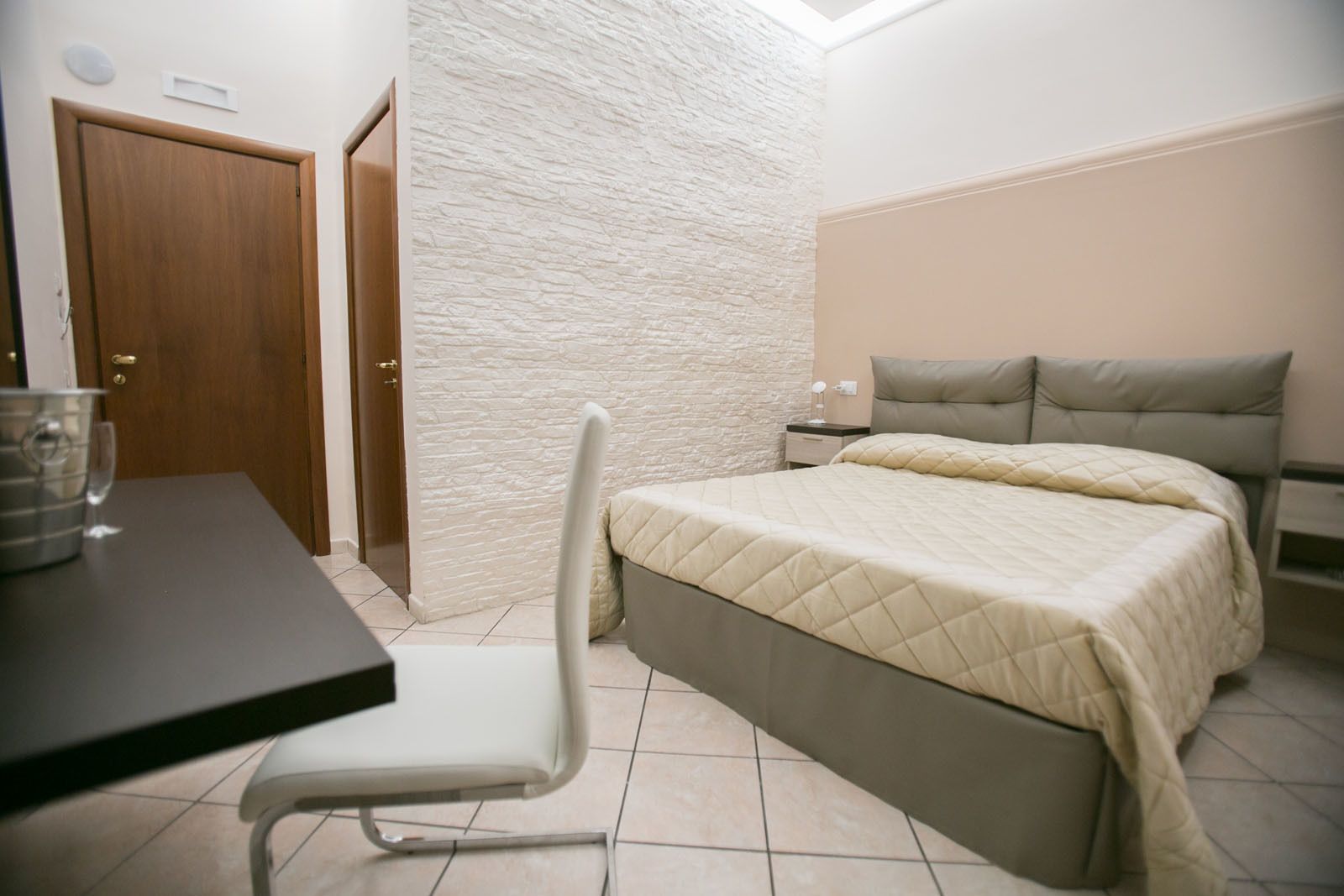 Ein Schlafzimmer mit Bett, Sessel, Nachttisch und Tisch.