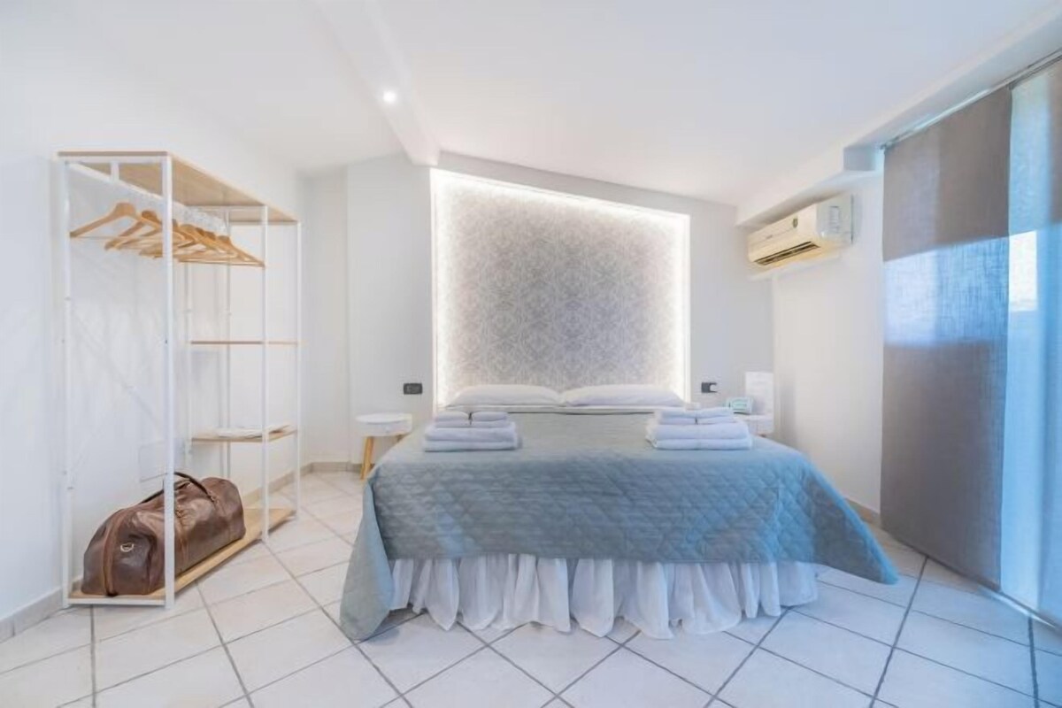 A modern bedroom with a bed, a wardrobe, and a built-in light panel.