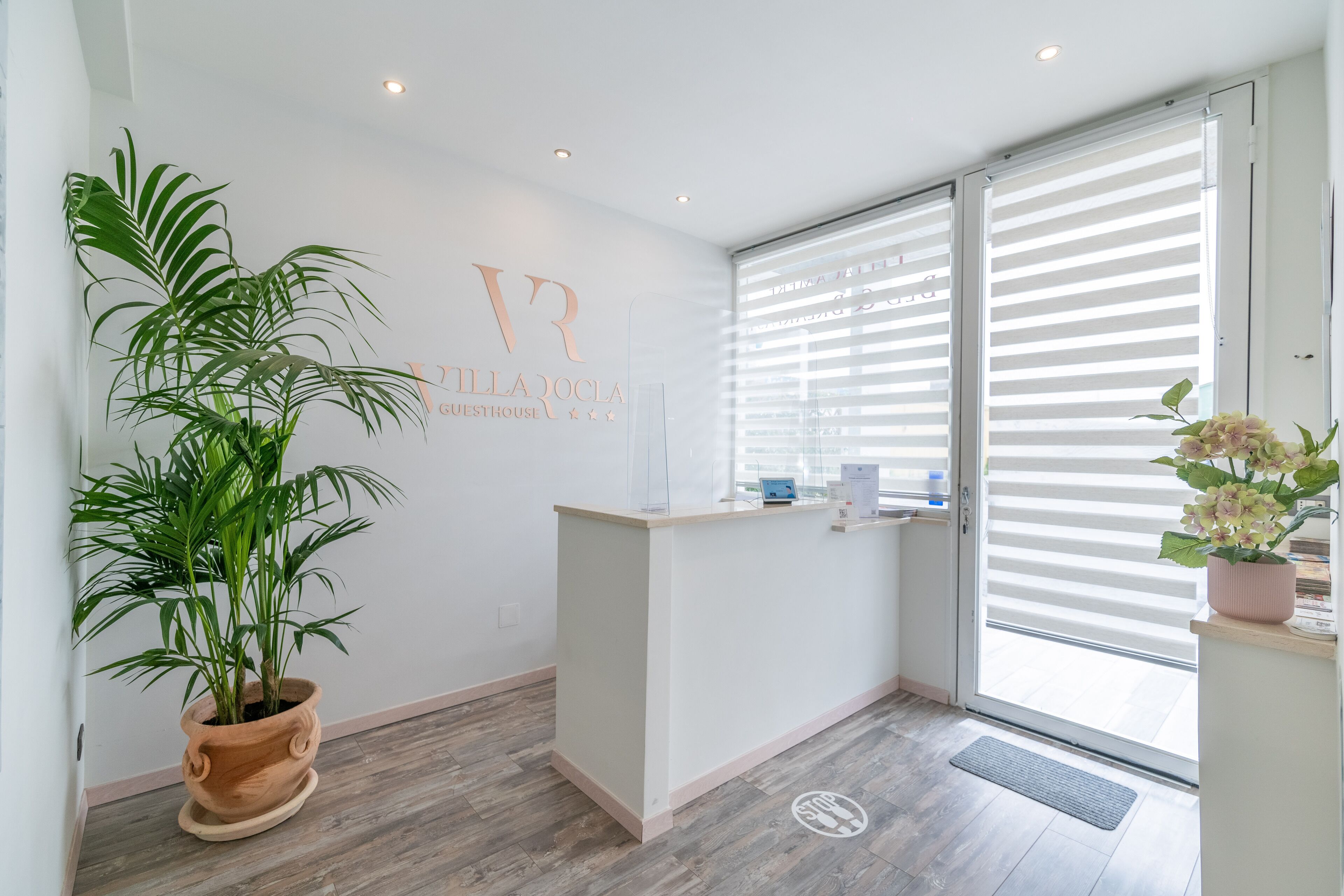 A reception area with a wooden reception desk, a potted plant, and a wall-mounted sign.