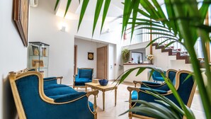 A spacious living area with blue upholstered chairs, a wooden coffee table, and a glass display cabinet. A staircase with a railing is visible in the background. - Villa Rocla Guest House Pompei (Pompei)