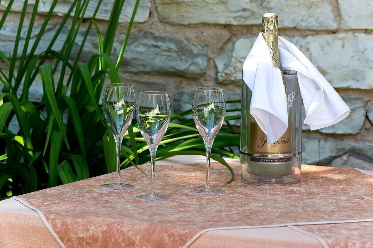 A bottle of champagne and three glasses on a table with a stone wall background.