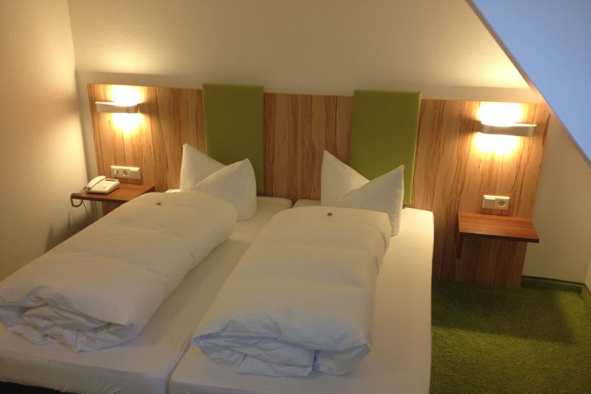 A twin room with two single beds, a bedside telephone, and two wall-mounted lamps.