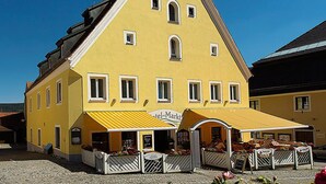 A yellow building with a triangular roof and multiple windows. - Hotel am Markt (Greding)