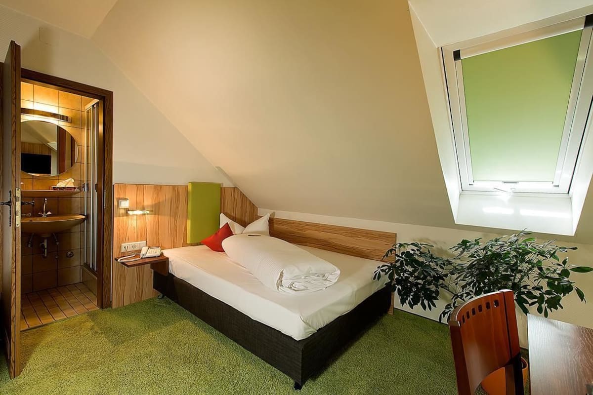 A bedroom with a bed, bedside table, and a window.
