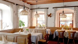 A restaurant with wooden beams, white tablecloths, and hanging lamps. - Hotel am Markt (Greding)