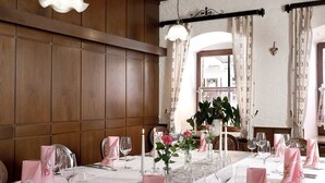 A dining area with a long table set for a meal, featuring pink napkins, clear glassware, and candles. - Hotel am Markt (Greding)