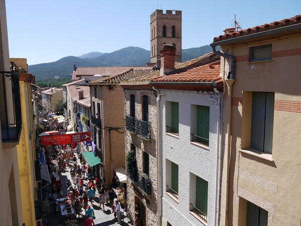 A crowded street with buildings, a tower, and mountains in the background.