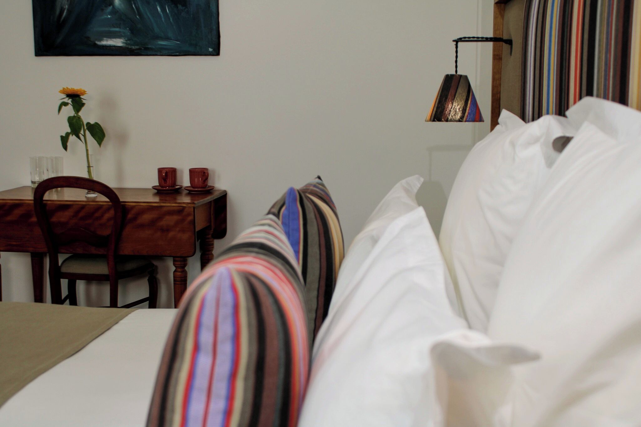 A hotel room with a bed, a small table with a vase of flowers, and a chair.