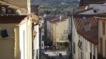 Una calle estrecha flanqueada por edificios, un letrero de 'Alimentation Seven-Up', y una colina a lo lejos.