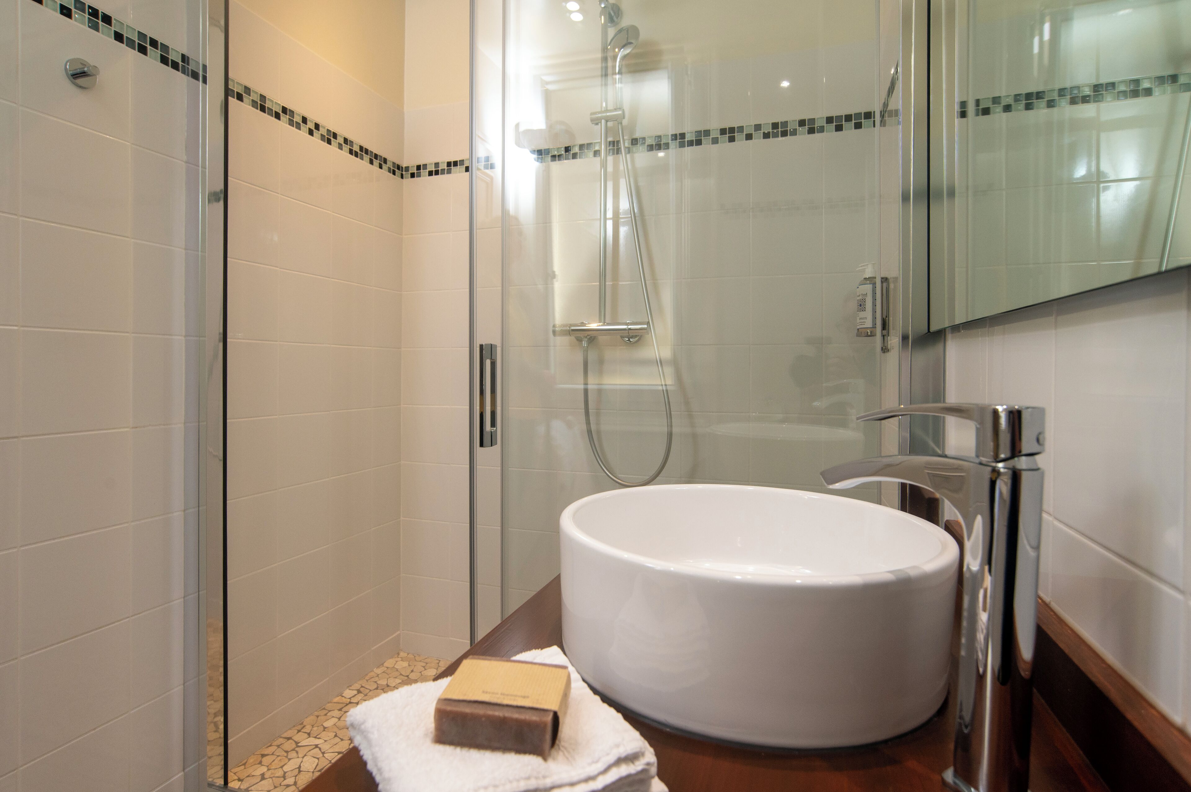 Une salle de bain moderne avec une douche à parois de verre, un grand lavabo blanc et un miroir au-dessus.