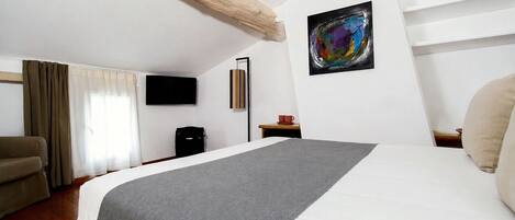 Habitación de hotel con cama, televisión, escritorio, silla y un cuadro en la pared.