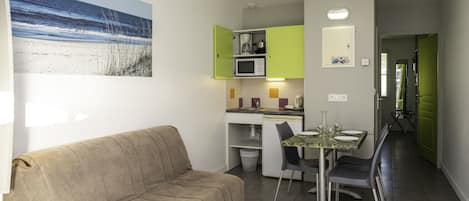 A compact living space with a kitchenette, a dining area, and a sofa.