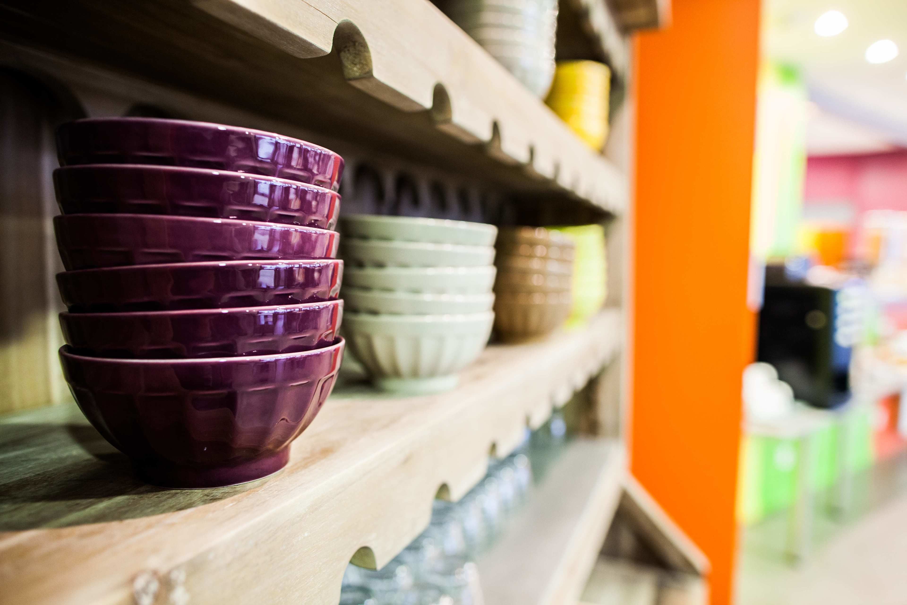 A shelf with stacked bowls of various colors.