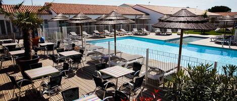 A poolside area with lounge chairs, umbrellas, and tables.