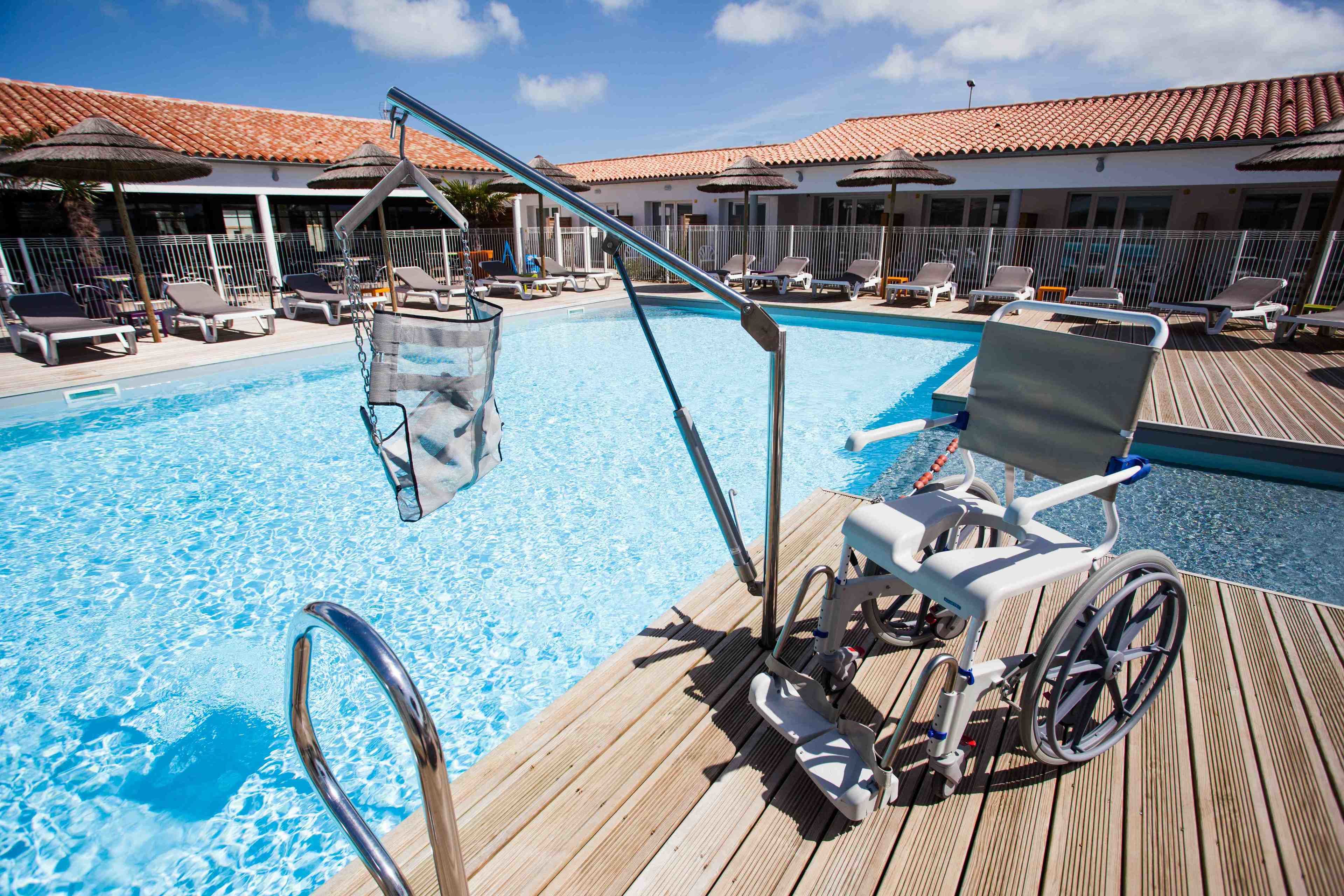 Ein Poolbereich mit Rollstuhl, Liegestühlen und Sonnenschirmen.