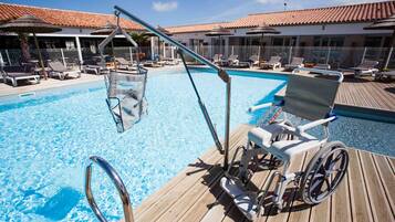 Ein Poolbereich mit Rollstuhl, Liegestühlen und Sonnenschirmen.
