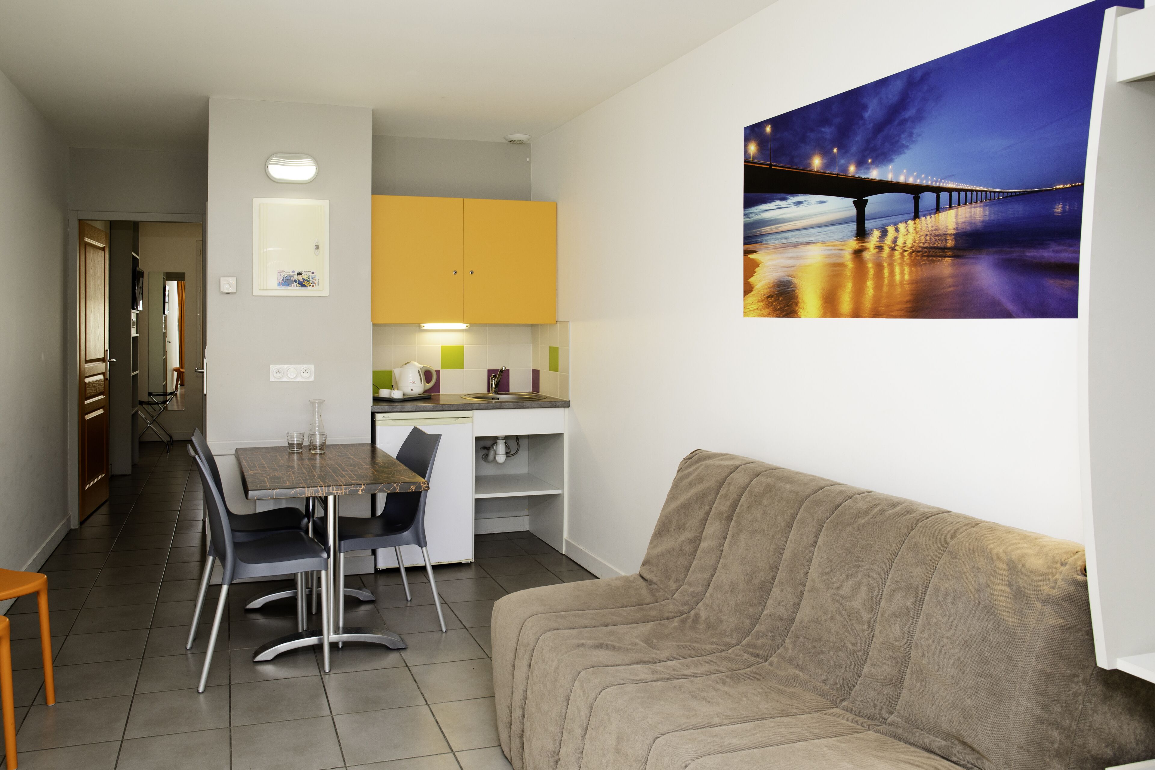 Eine moderne Küche mit Essbereich, einer Couch und einem Gemälde einer Brücke.