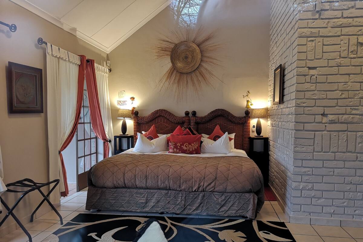 Ein Hotelzimmer mit einem großen Bett, einer dekorativen Deckenleuchte und einer Ziegelwand.