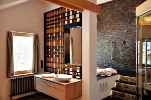 Une salle de bain moderne avec un meuble-lavabo en bois, un grand miroir et un mur en pierre.
