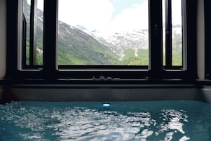 Janela com vista para uma paisagem montanhosa e uma piscina em primeiro plano.