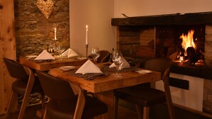 Une salle à manger avec un mur en pierre, une cheminée et une table dressée pour quatre personnes.