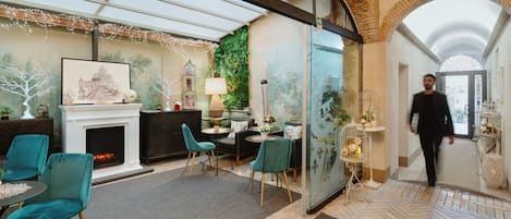 Un interior moderno con chimenea, sillas color turquesa, zona de comedor y separador de vidrio.