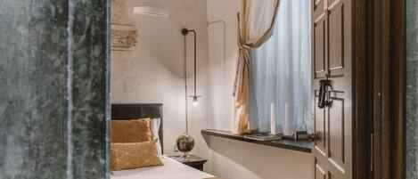 A bedroom with a bed, a nightstand, a lamp, a globe, and a window with curtains.