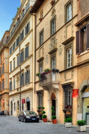 A historic street with cobblestone pavement, classic European architecture, and a parked car. - Relais Giulia (Rome)