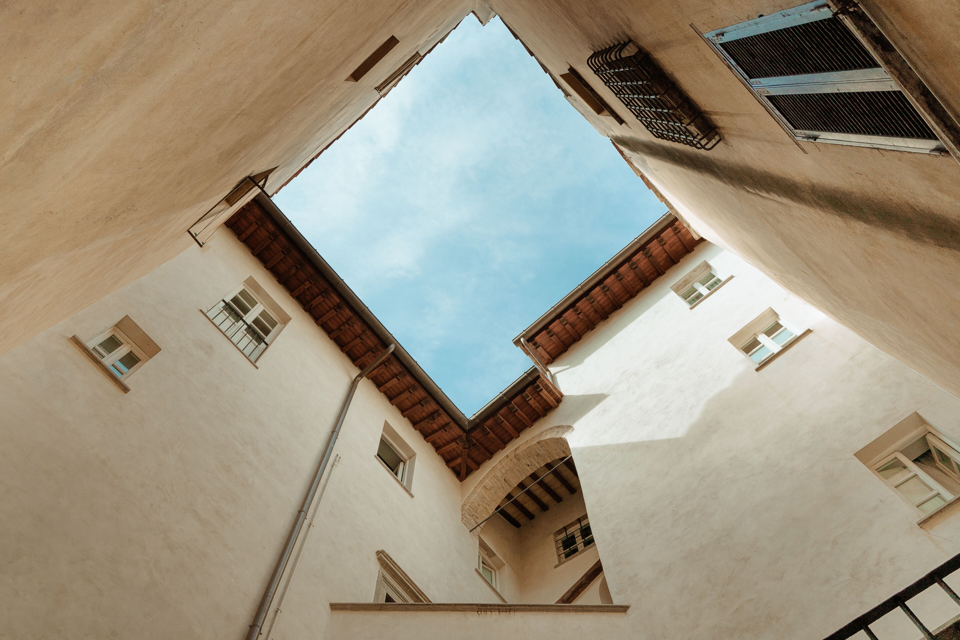 Un edificio con un patio central, varias ventanas y un cielo despejado visible a través del espacio abierto.