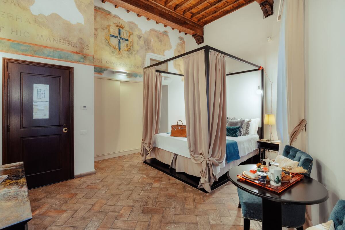 A bedroom with a four-poster bed, a wooden door, a map mural, and a dining table with breakfast items.