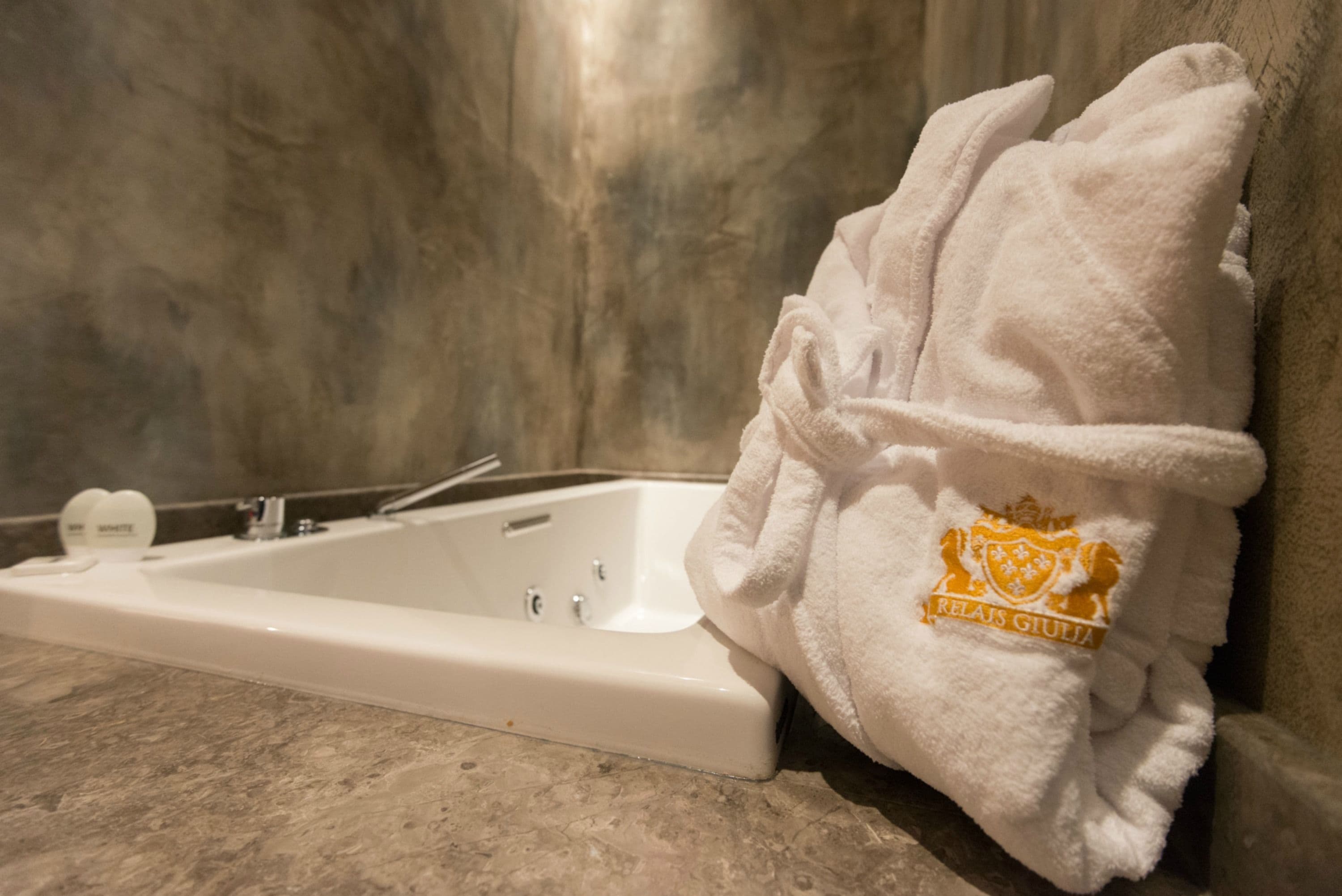 A bathroom with a bathtub, a towel, and a bottle of shampoo.