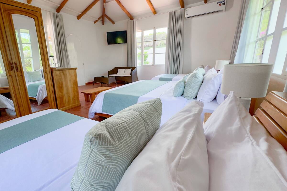 A hotel room with two beds, a wooden wardrobe, a television, and a window with curtains.