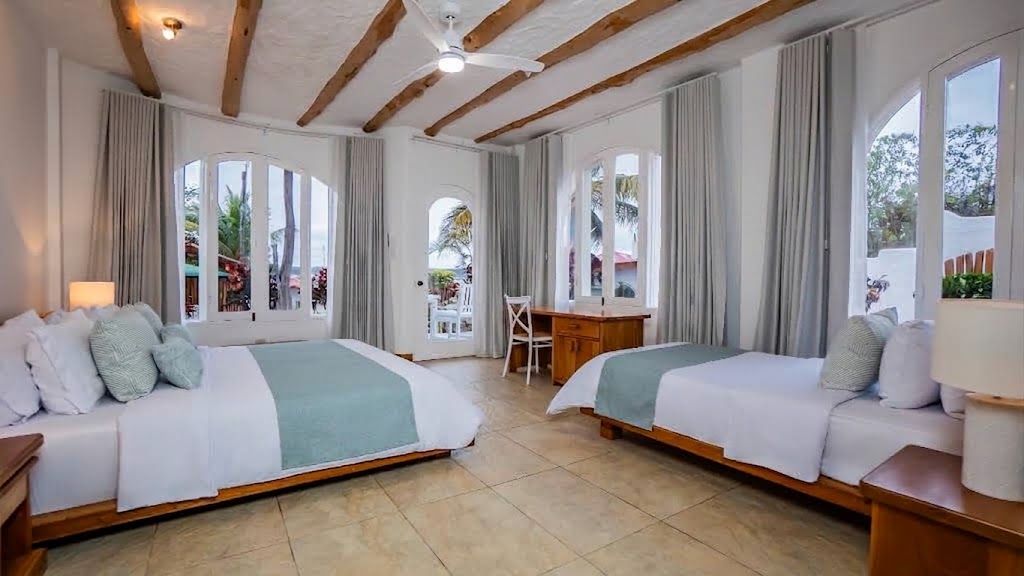 Een hotelkamer met twee bedden, een bureau en grote ramen.