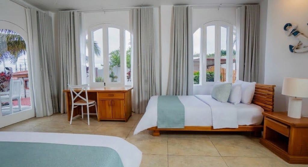 Habitación de hotel con cama, escritorio y silla. Hay cortinas en las ventanas.