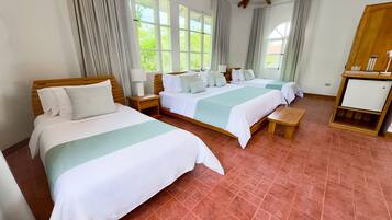 A hotel room with two beds, a wooden bench, a nightstand with a lamp, and a small cabinet.