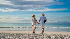 A couple holding hands on a beach with the ocean in the background. - Angermeyer Waterfront Inn (Puerto Ayora)