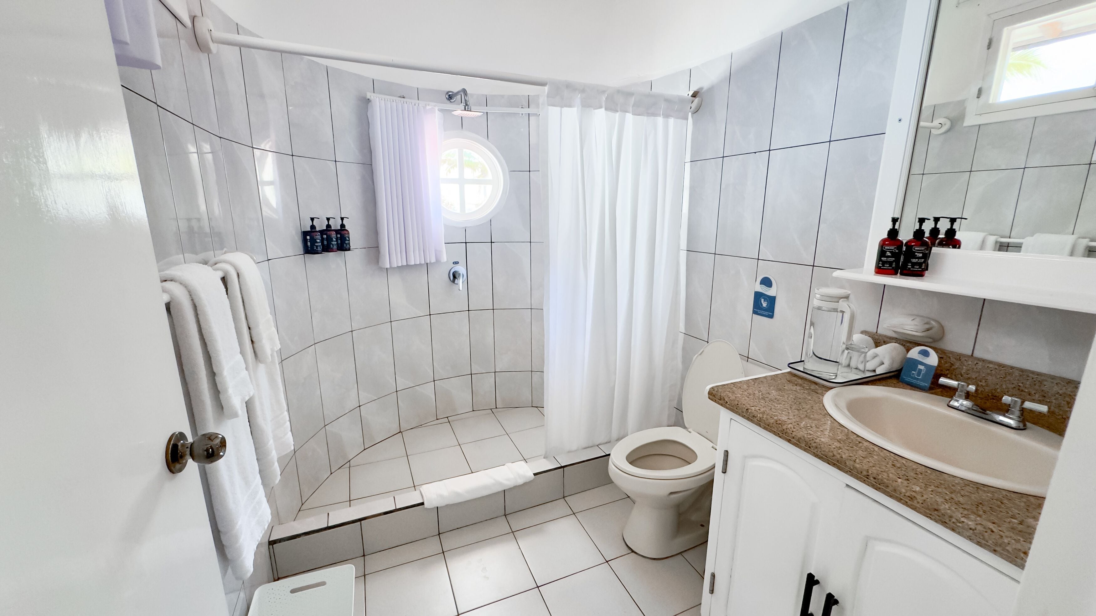 A bathroom with a shower, toilet, sink, and a towel rack.