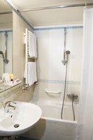 Un bagno con vasca, lavabo incassato in vetro e doccia dotata di soffione manuale.