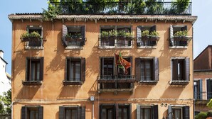 Un edificio de varios pisos con balcones, un restaurante y el letrero de un hotel.