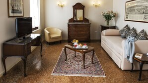 Una sala de estar con sofá, sillón, cómoda de madera y televisor.