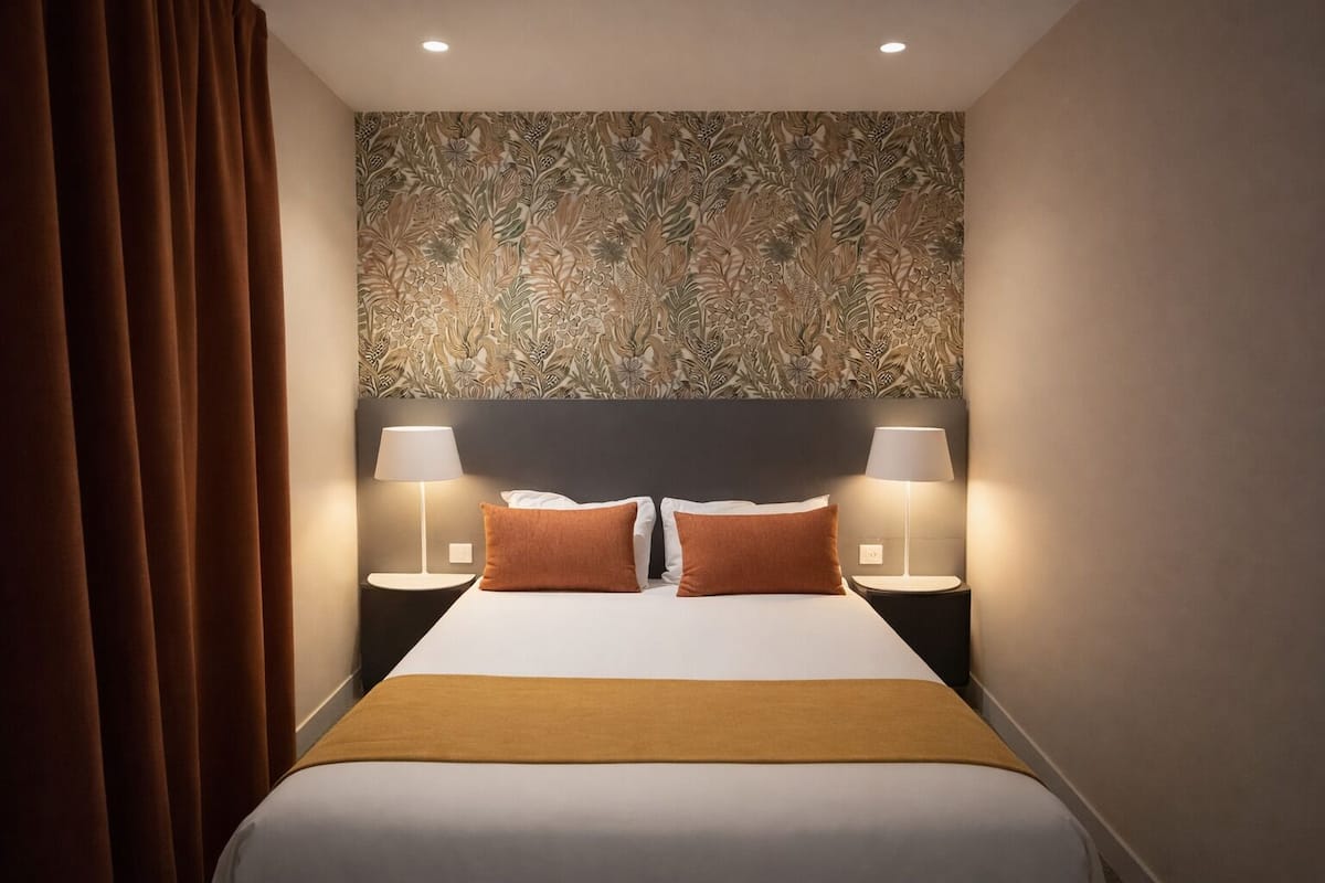 A hotel room with a large bed, two bedside lamps, and a decorative wall panel.