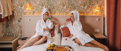 A hotel room with a bed, a tray with fruits and a pizza, and a wall with a floral pattern.