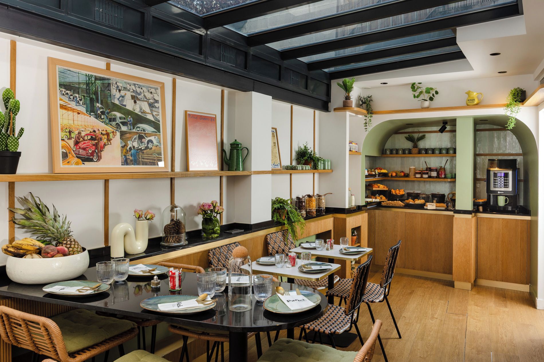 Ein Restaurant mit einer langen Theke, mehreren Tischen und Stühlen. An den Wänden befinden sich Pflanzen und Kunstwerke.