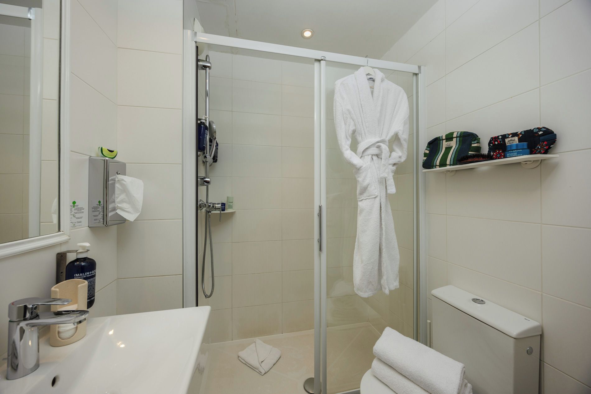 Une salle de bain moderne avec une douche à l’italienne en verre, une baignoire blanche et un meuble-lavabo avec un miroir.