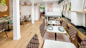 Un restaurante moderno con techo alto y tragaluces, que ofrece una variedad de opciones de asiento y una zona de comedor central.