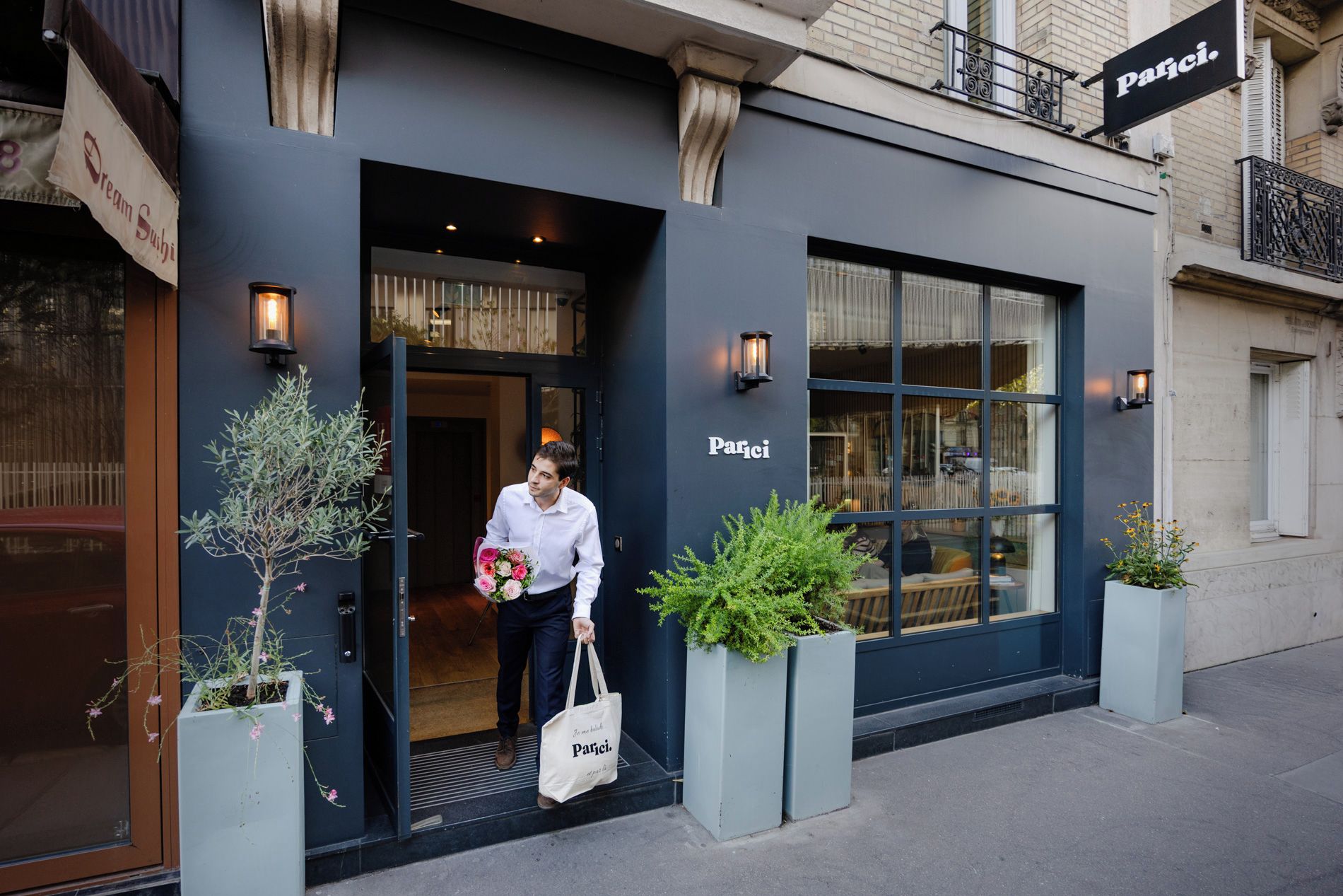 A building with a sign reading 'Parici' and a person exiting with a bag.