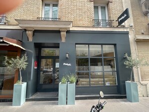 A building with a black facade, a sign reading "Parici," and two potted plants in front. - Parici Hotel Boulogne Billancourt (Boulogne-Billancourt)