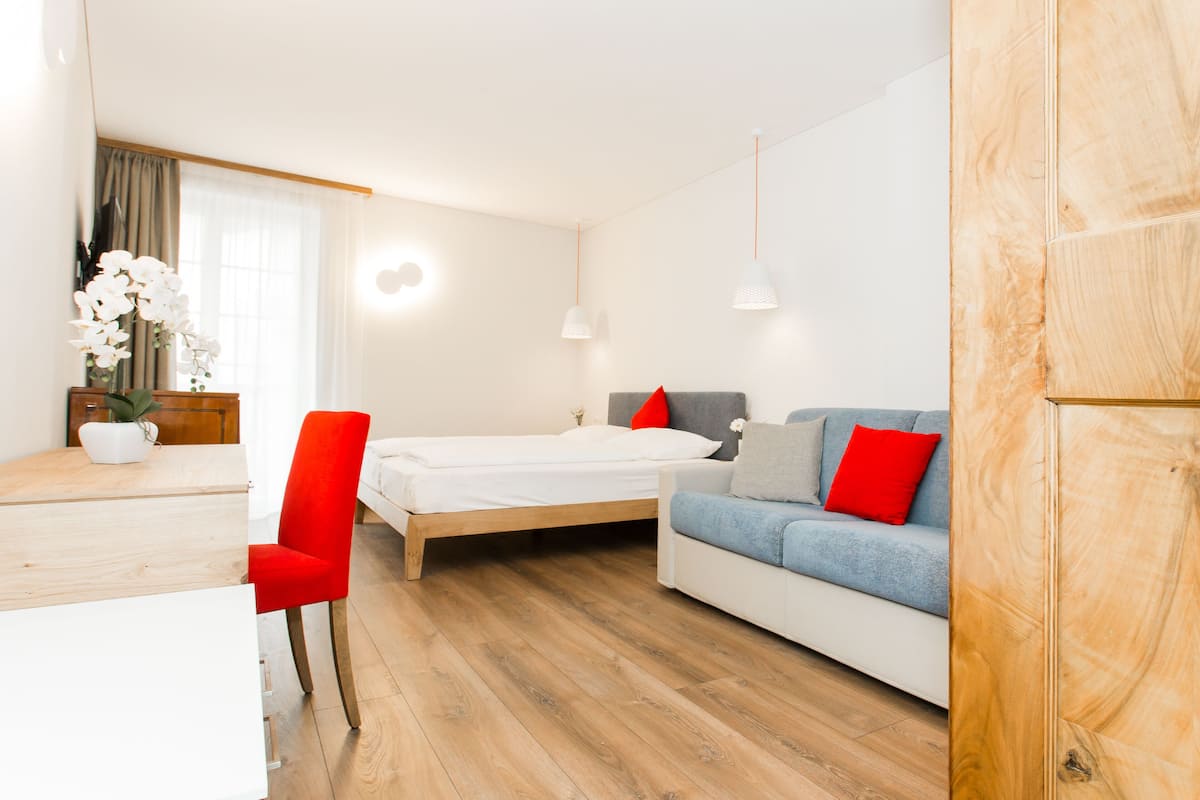Una habitación moderna con cama, sofá, mesa de comedor y una silla.