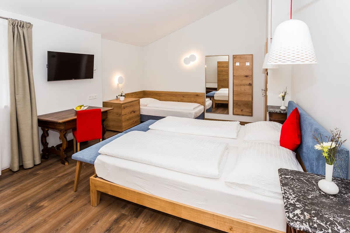 Una habitación de hotel moderna con una cama de madera, un escritorio, una silla, un televisor y un espejo.